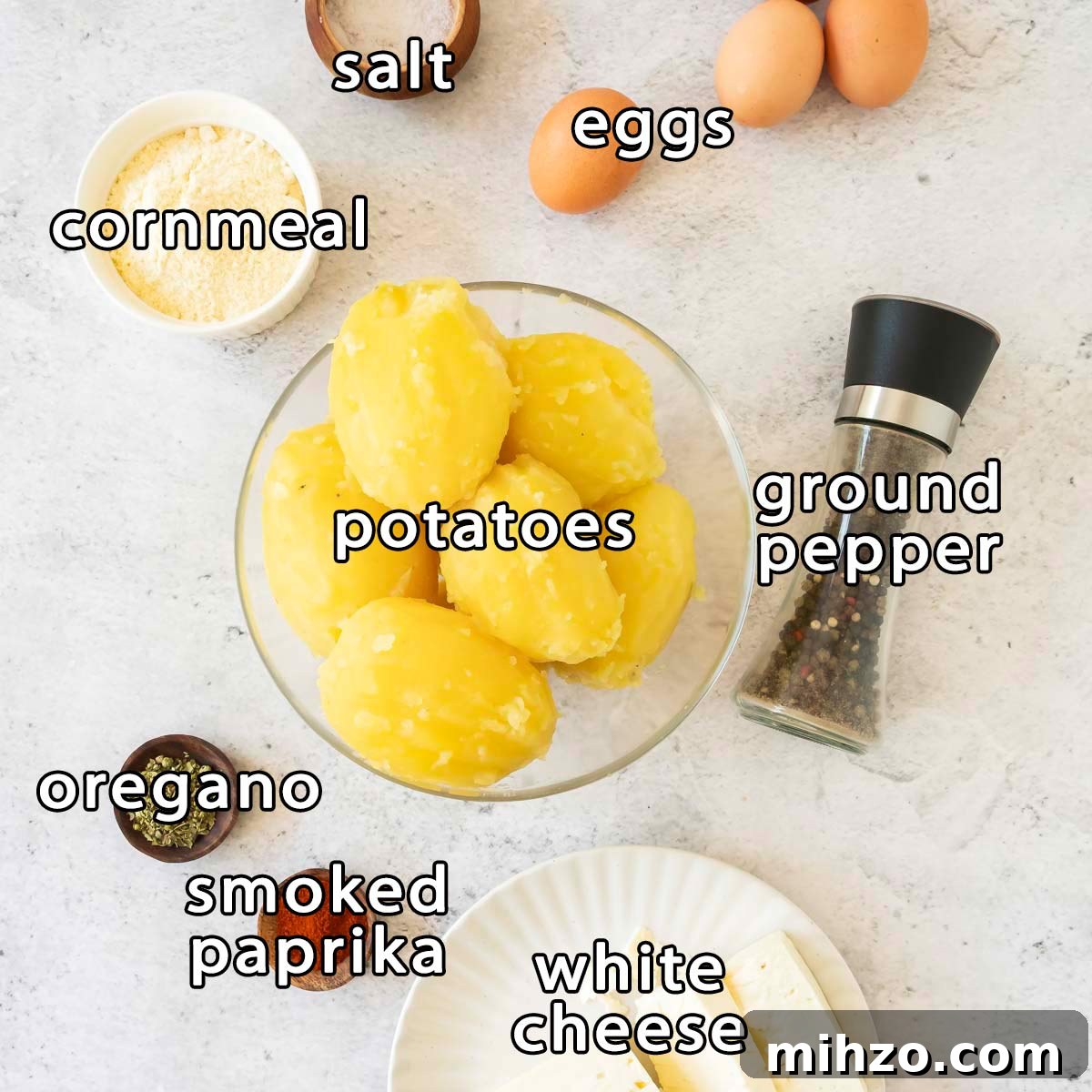 Crispy Potato Fritters Recipe — Golden Pan-Fried Latkes 3 Overhead shot of ingredients - - cornmeal, salt, eggs, potatoes, ground pepper, oregano, smoked paprika, and white cheese.