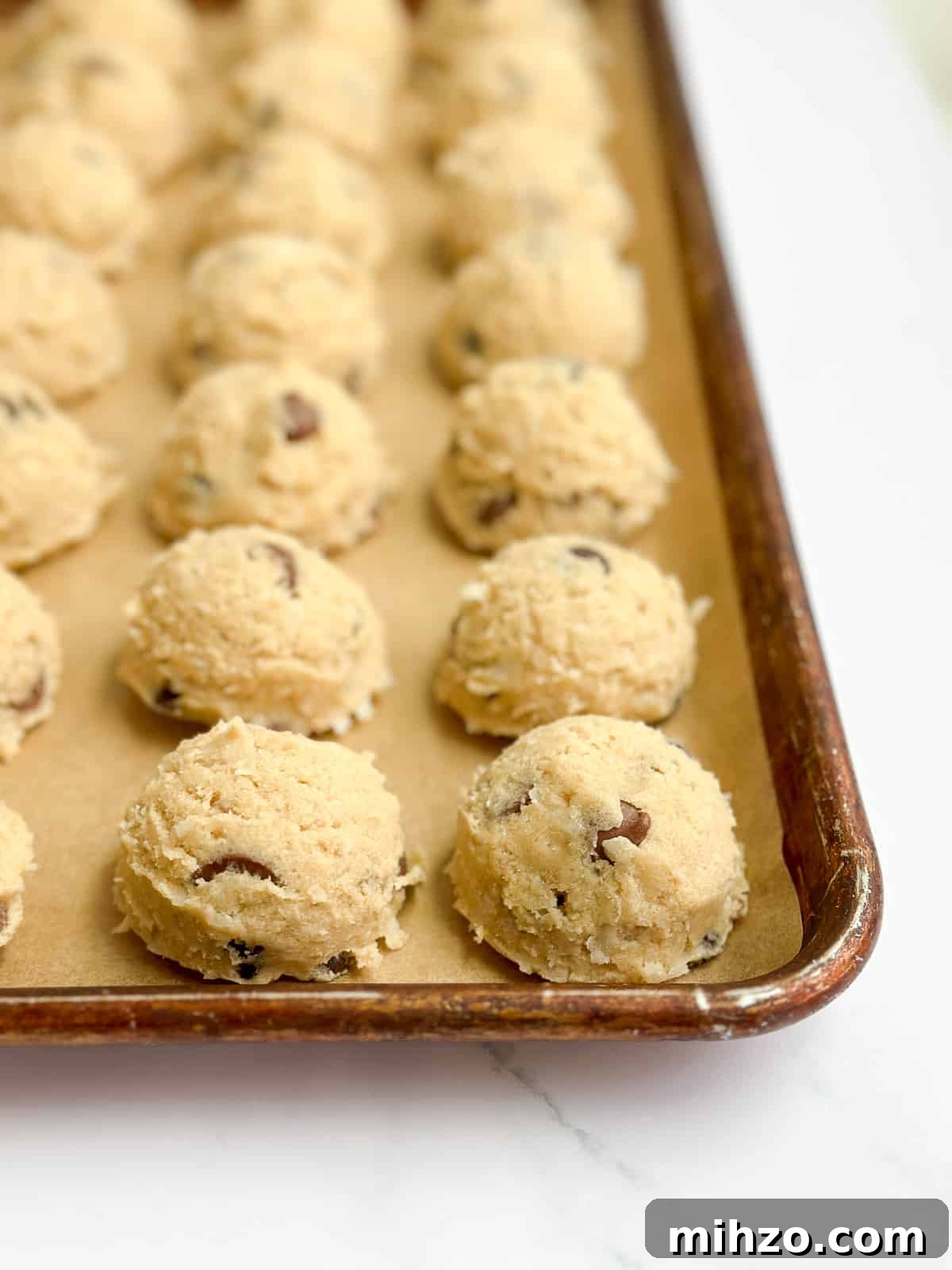 a lot of chocolate chip coconut cookie dough lined on a baking sheet.