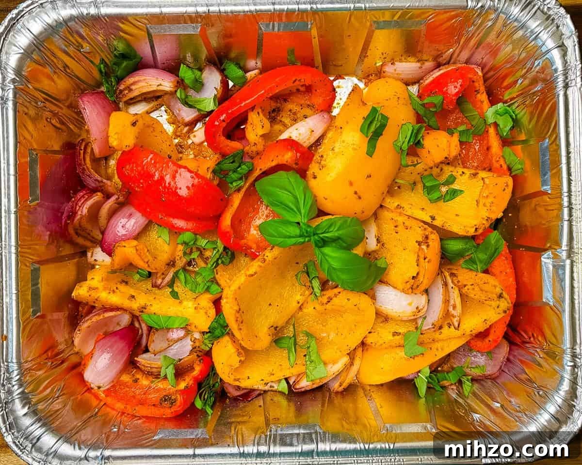 Smoked peppers and onions in a foil pain, garnished with fresh basil.