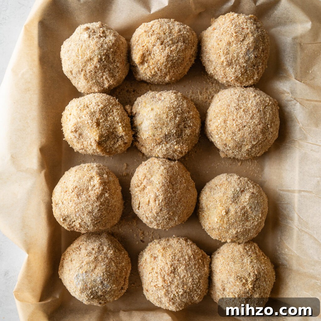 boudin balls coated in bread crubs on a parchment lined sheet pan