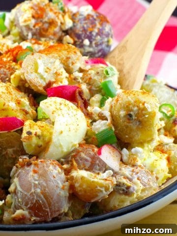Pierogi Potato salad in a Ukrainian print dish with wooden spoon and checkered red and white towel in the background