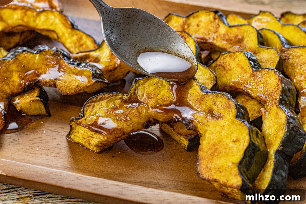Crispy Roasted Acorn Squash in the Air Fryer 3 spoon drizzling cinnamon butter over cooked acorn squash slices