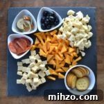 Meat and Cheese Board on gray slate with white bowls for olives and pepperoni.