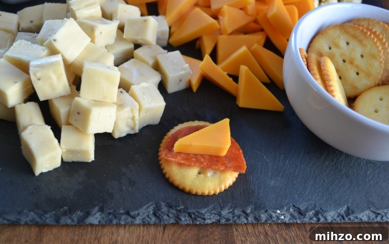 Meat and Cheese Snack Board with three kinds of cheese with close up of cheese and pepperoni on a cracker.