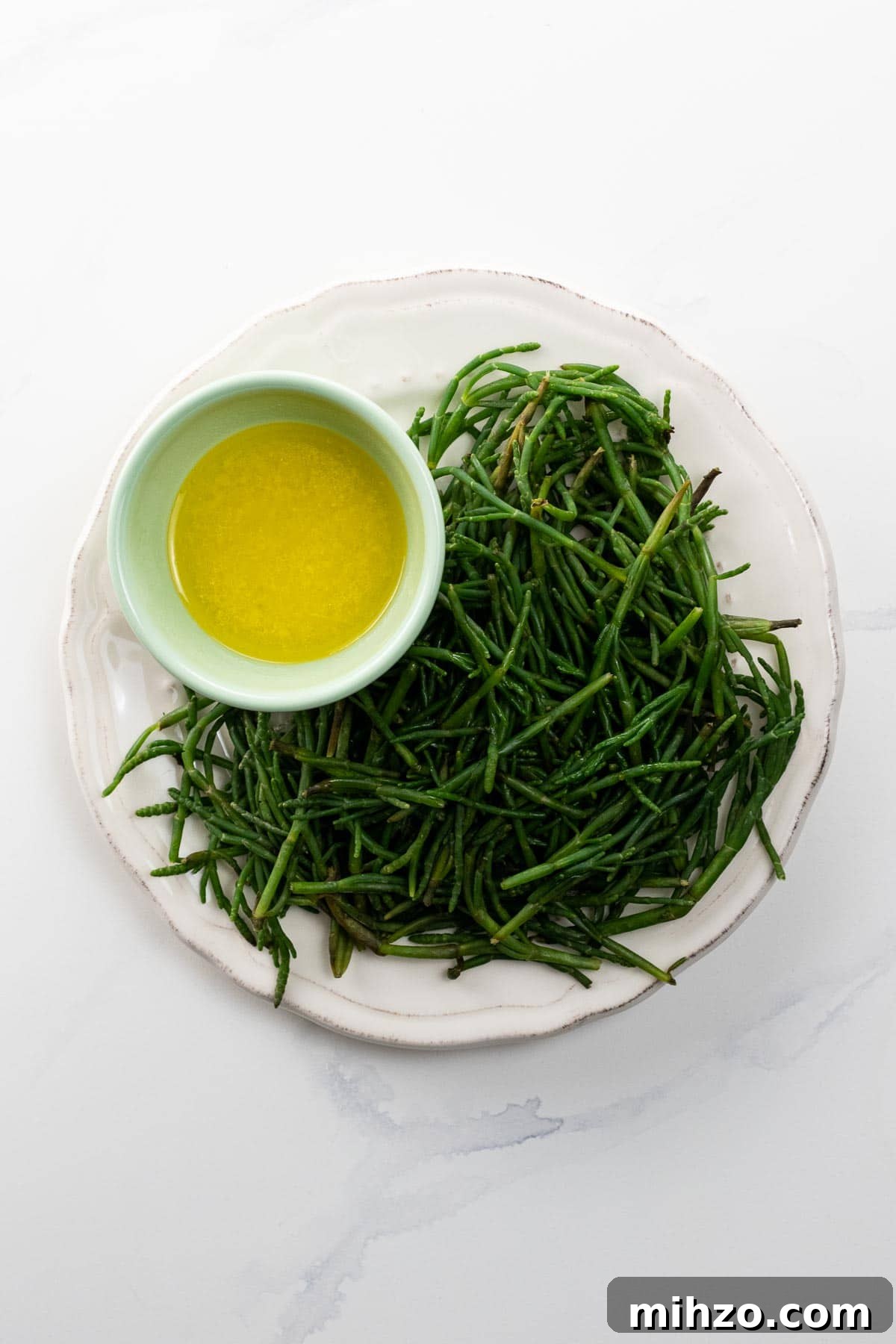 How to Cook Sea Beans (Samphire) — Simple Salicornia & Glasswort Recipe 2 sea beans on a plate with a bowl of lemon butter for dipping