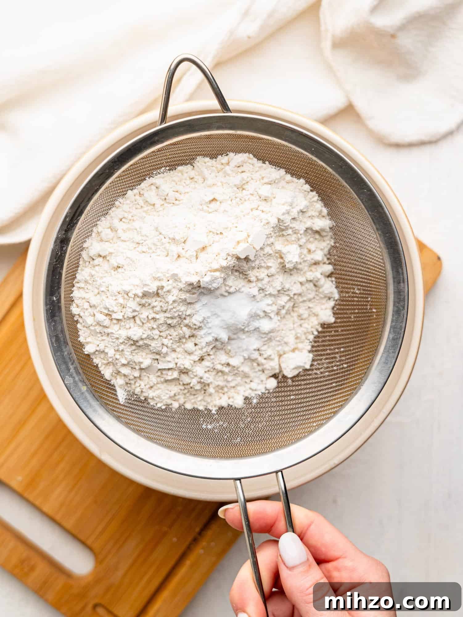 Sifting dry ingredients into a mixing bowl.