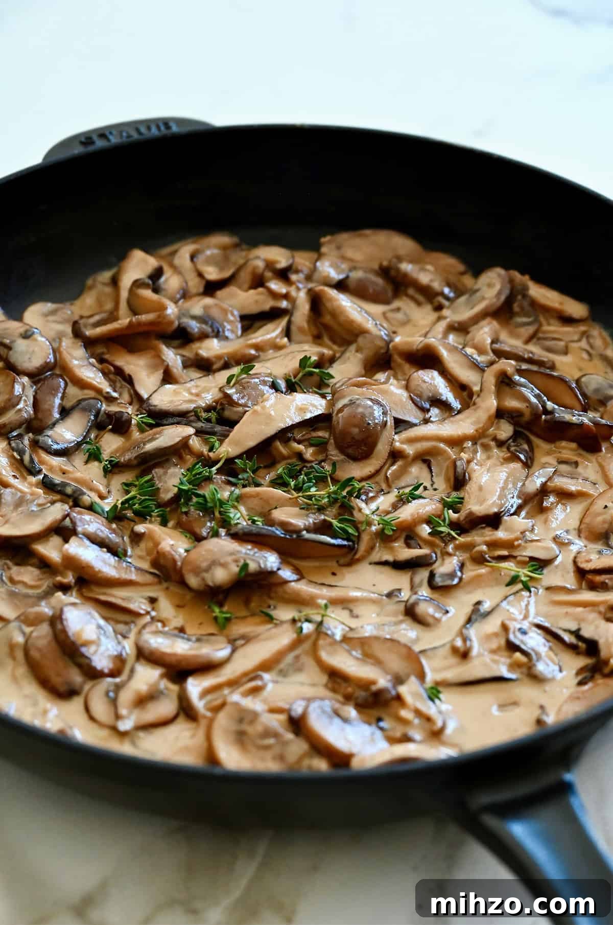 Creamy Garlic Mushroom Sauce for Pasta and Steak 9 Mushroom cream sauce in a large skillet, garnished with fresh thyme leaves.