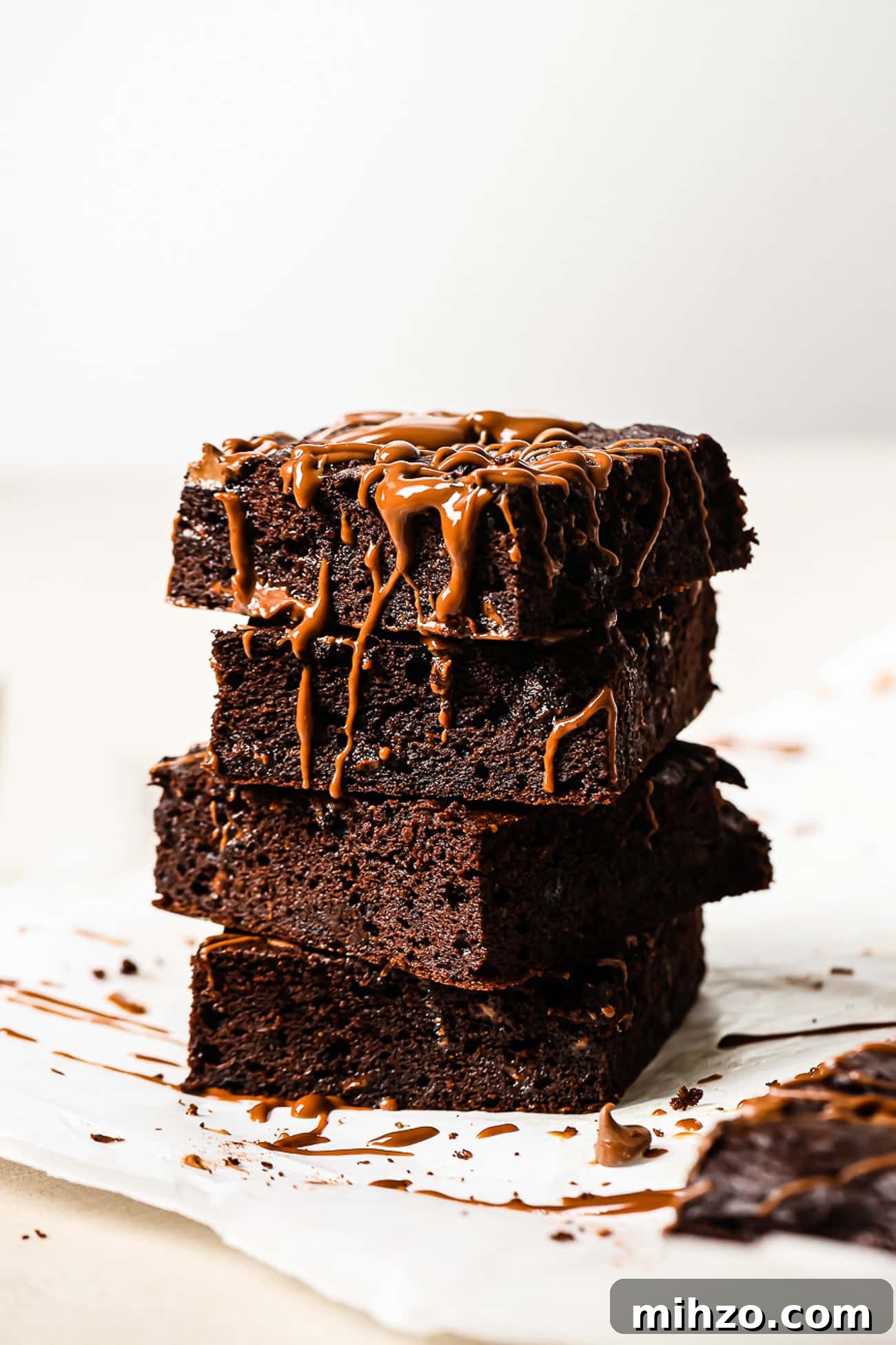 Fudgy Pumpkin Brownies with Warm Spice Flavor 2 A stack of healthy pumpkin brownies topped with chocolate drizzle.