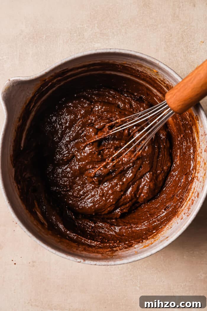 Fudgy Pumpkin Brownies with Warm Spice Flavor 4 Peanut butter and pumpkin puree in a large bowl with a whisk in it.