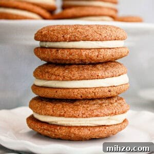 Gingerbread Sandwich Cookies Recipe for the Holidays 11 Gray background with stack of gingerbread sandwich cookies on a white plate.