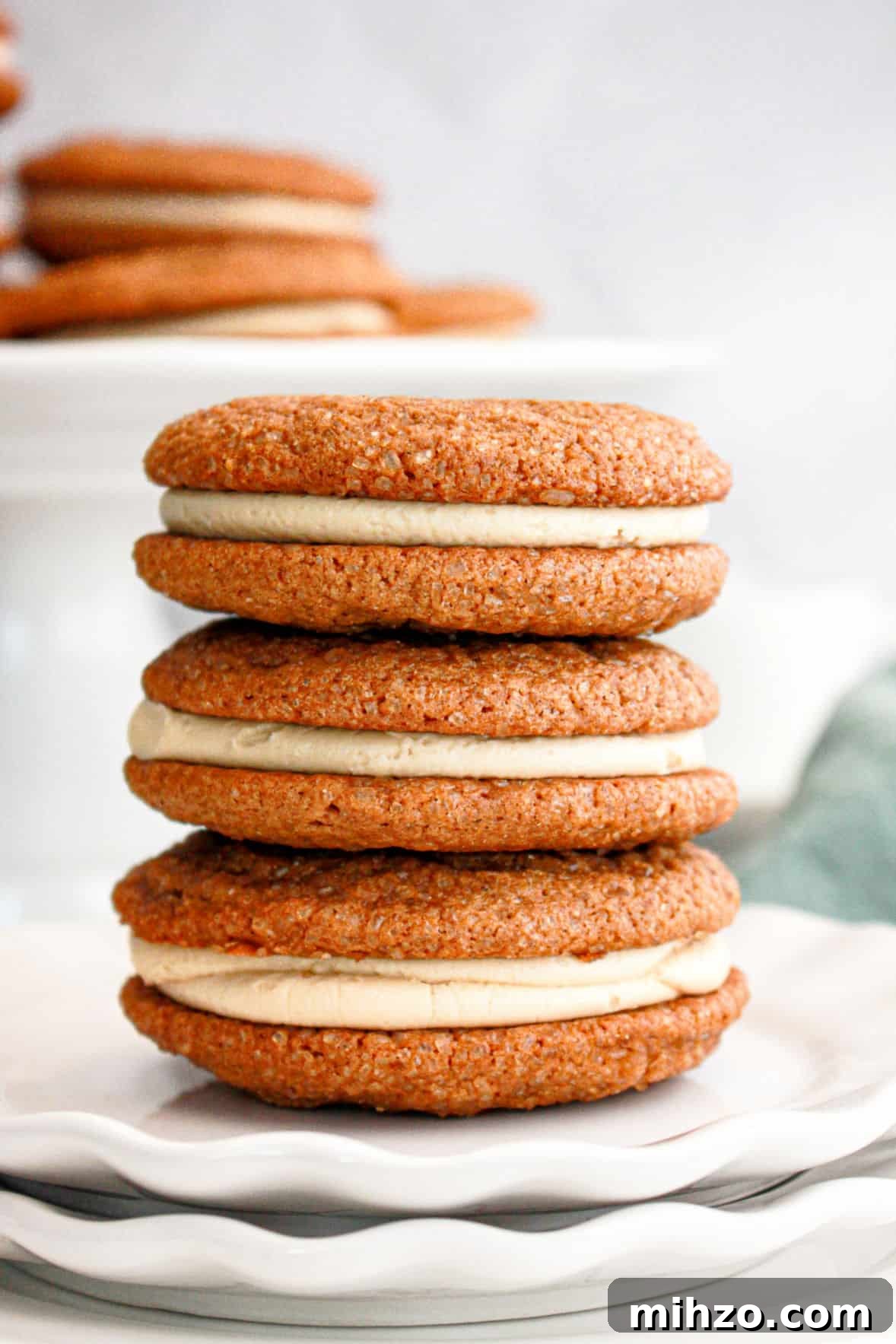 Gingerbread Sandwich Cookies Recipe for the Holidays 3 Stack of three gingerbread sandwich cookies on white plates. Light gray background.