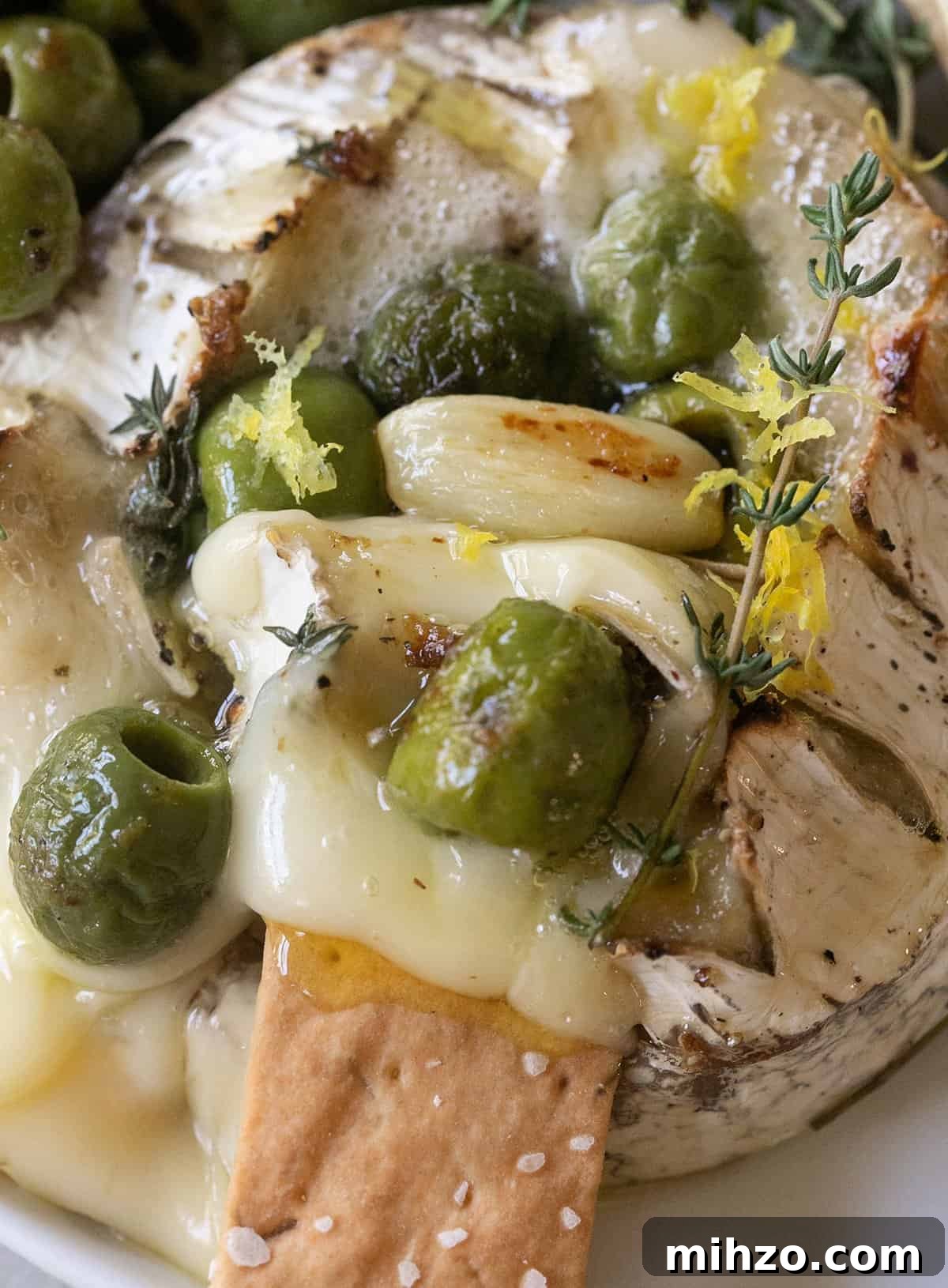 Cheesy baked brie with melted center and savory olive topping, ready to serve.
