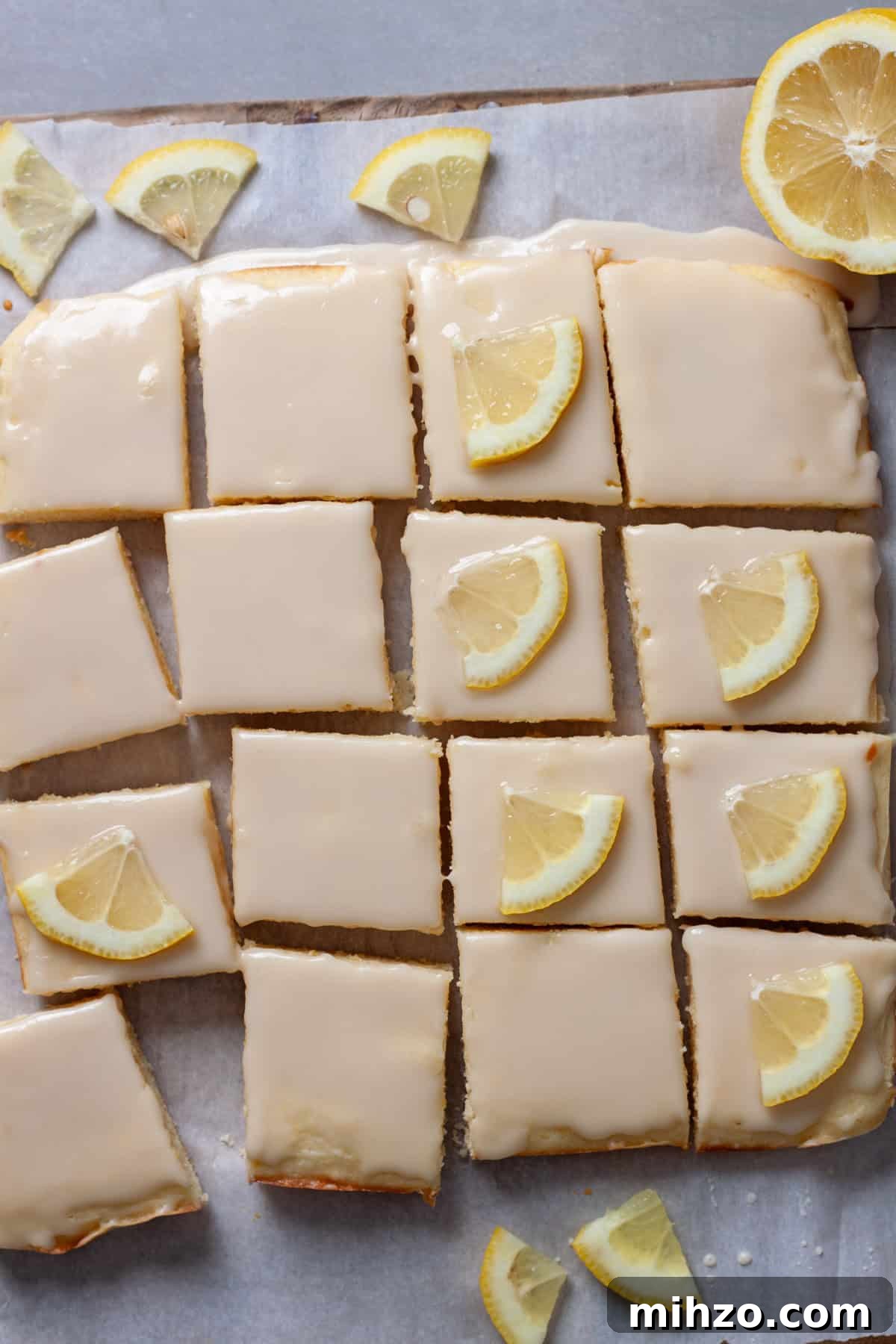 Zesty Lemon Blondies with Luscious Glaze 13 Thin slices of lemons pressed on top of lemon blondies on a piece of parchment paper.