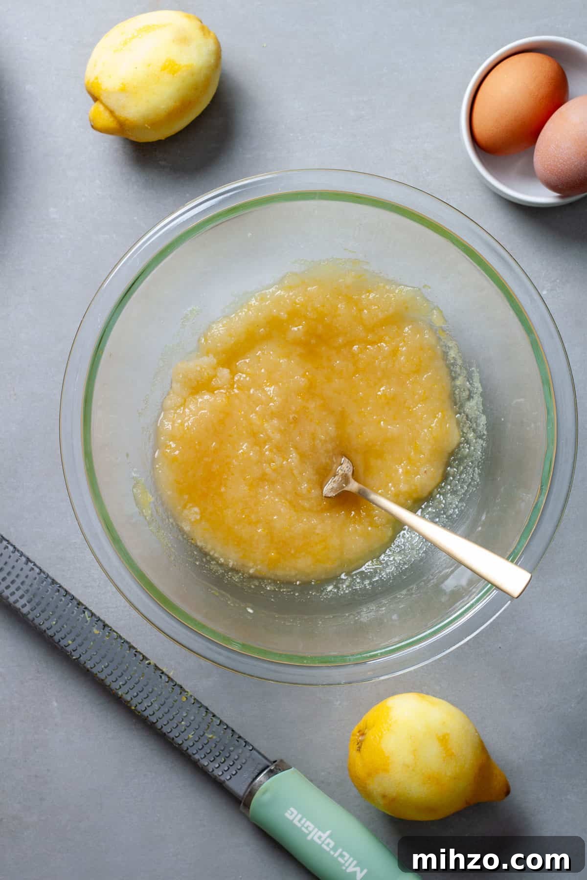 Zesty Lemon Blondies with Luscious Glaze 6 Wet ingredients for lemon and vanilla blondies in a glass bowl on a gray table.