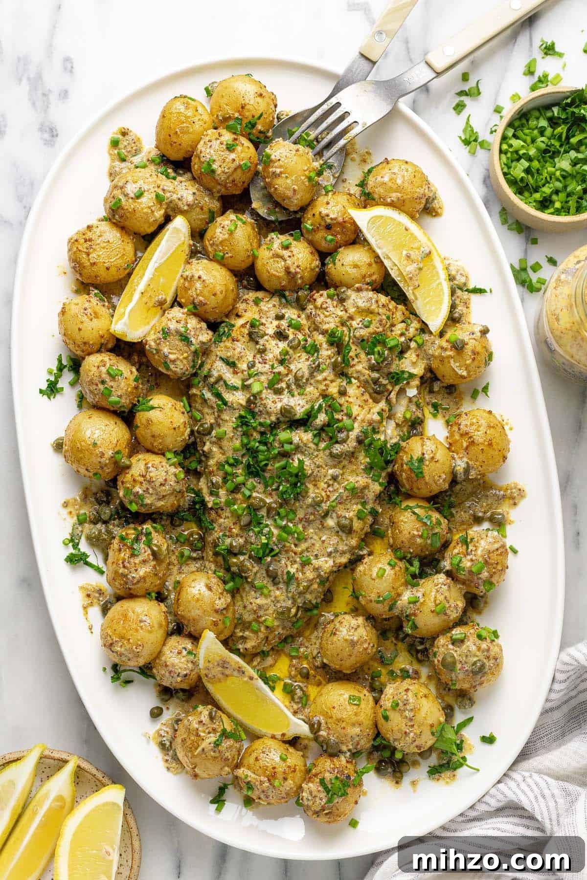 Oven-Baked Fish and Potatoes in Creamy Mustard Sauce 2 Serving platter filled with roasted potatoes and baked fish in mustard sauce.