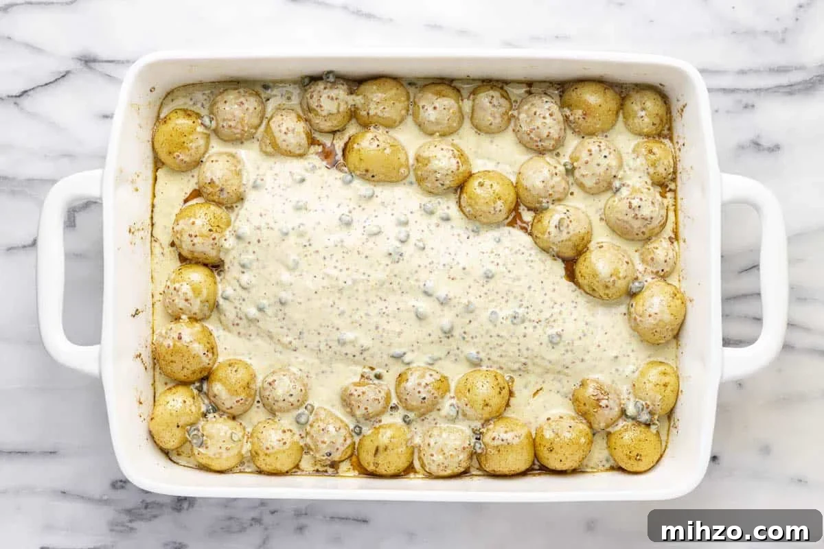 Oven-Baked Fish and Potatoes in Creamy Mustard Sauce 5 Mustard sauce poured over fish and potatoes in a large baking dish.