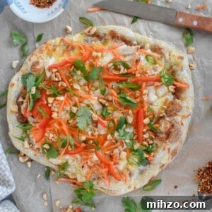 Thai Chicken Pizza Recipe: Tangy Peanut Sauce & Crispy Crust 12 whole pizza on brown parchment paper.