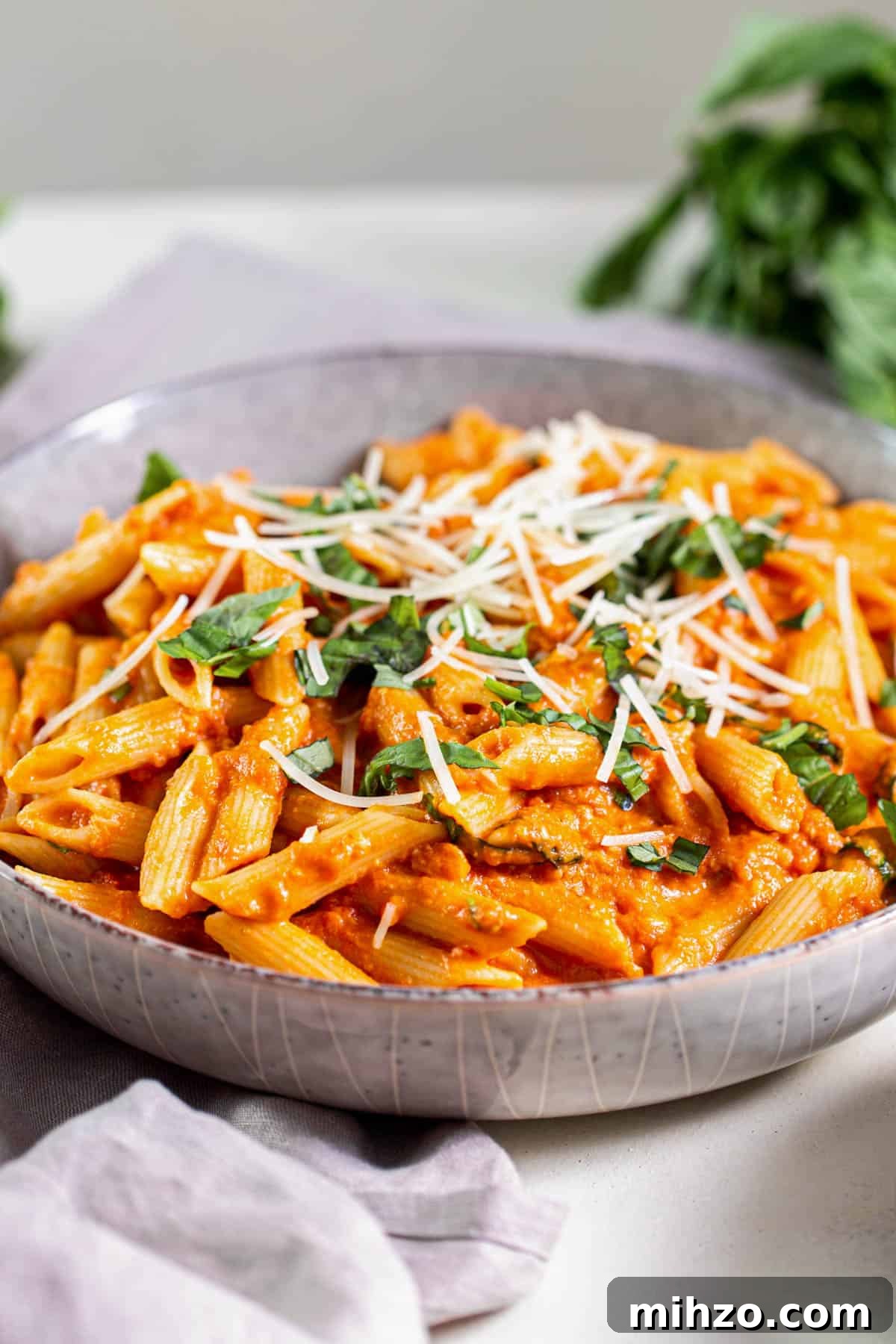 Quick Tomato and Basil Pasta Recipe in 20 Minutes 4 A large bowl filled with cooked tomato basil pasta that is topped with chopped basil and shredded Parmesan cheese.