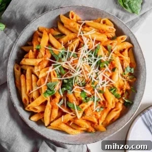 Quick Tomato and Basil Pasta Recipe in 20 Minutes 6 A bowl filled with tomato basil pasta with fresh Parmesan and basil sprinkled on top.