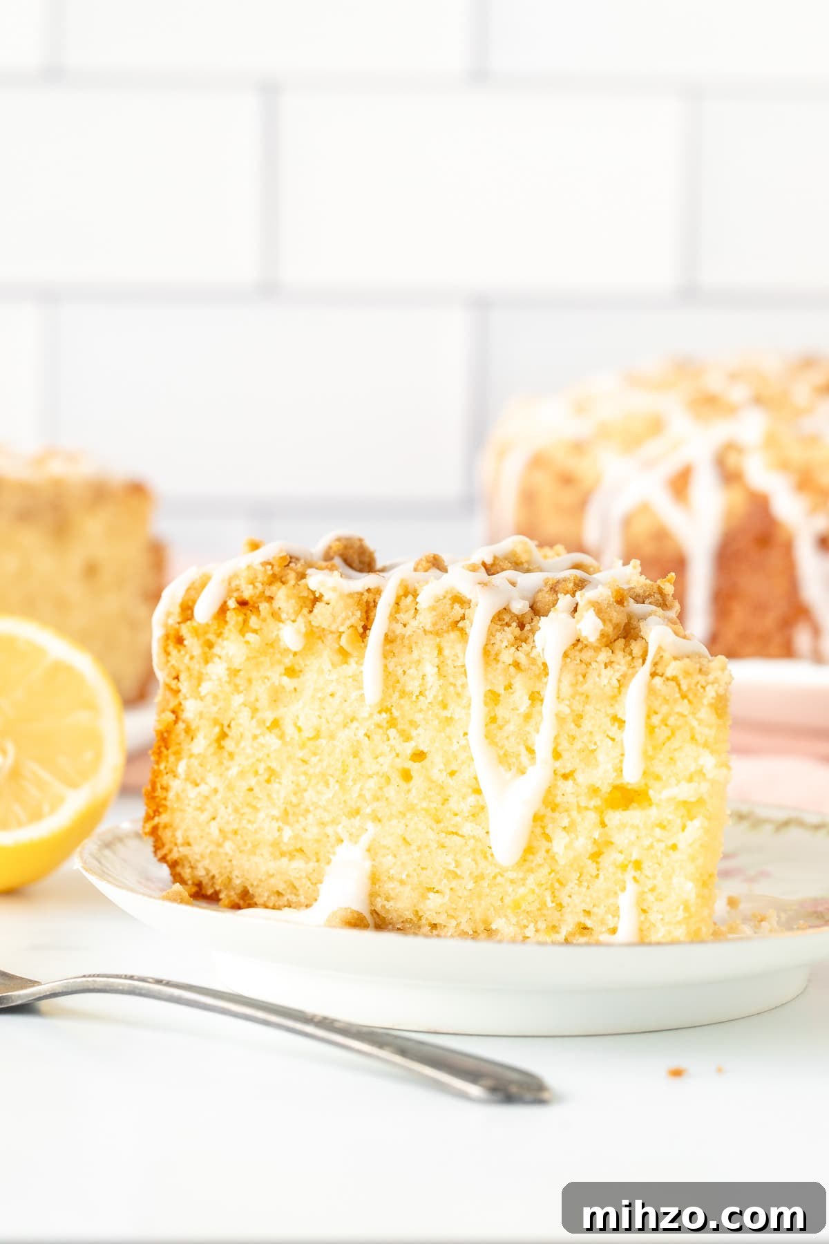 Lemon Coffee Cake Recipe — Moist Citrus Loaf for Brunch 2 Slice of lemon coffee cake with crumb topping and drizzle of glaze