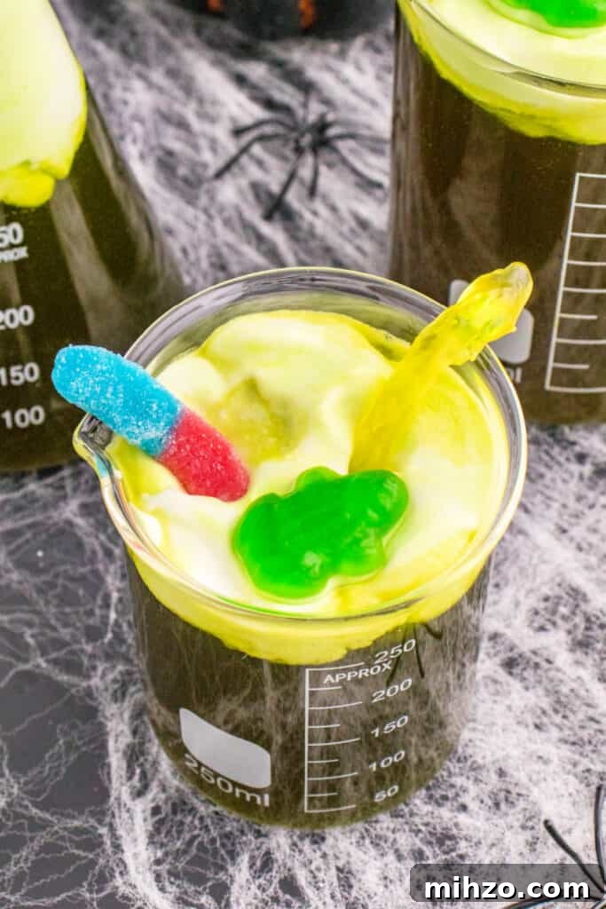 Toxic Waste Punch Recipe: How to Make a Neon Party Drink 17 Beaker of Toxic Waste Punch with gummy frog and gummy worm toppings, showcasing the foamy toxic waste effect.