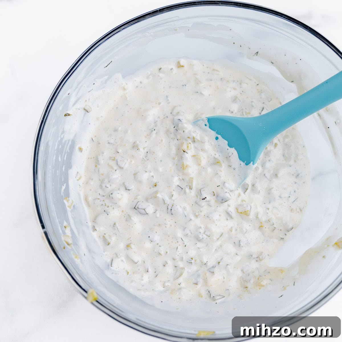 Creamy Homemade Tartar Sauce for Seafood 4 A clear bowl with tartar sauce and a blue spatula