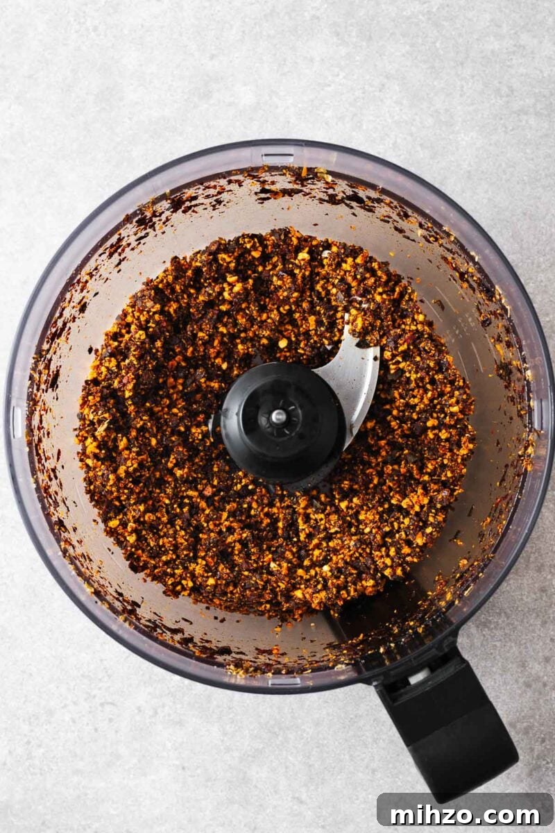 A food processor with coarsely blended fried garlic, chillies and cashew nuts.