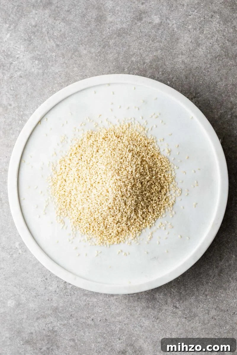 A marble plate with raw sesame seeds. The sesame seeds are white and hulled.