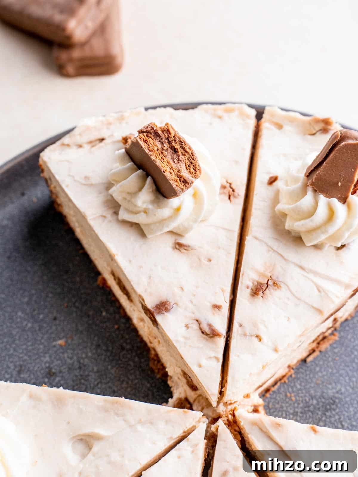 Decadent Tim Tam Cheesecake Recipe You’ll Love 2 top view of Tim Tam Cheesecake sliced into triangles and decorated with whipped cream and Tim Tams