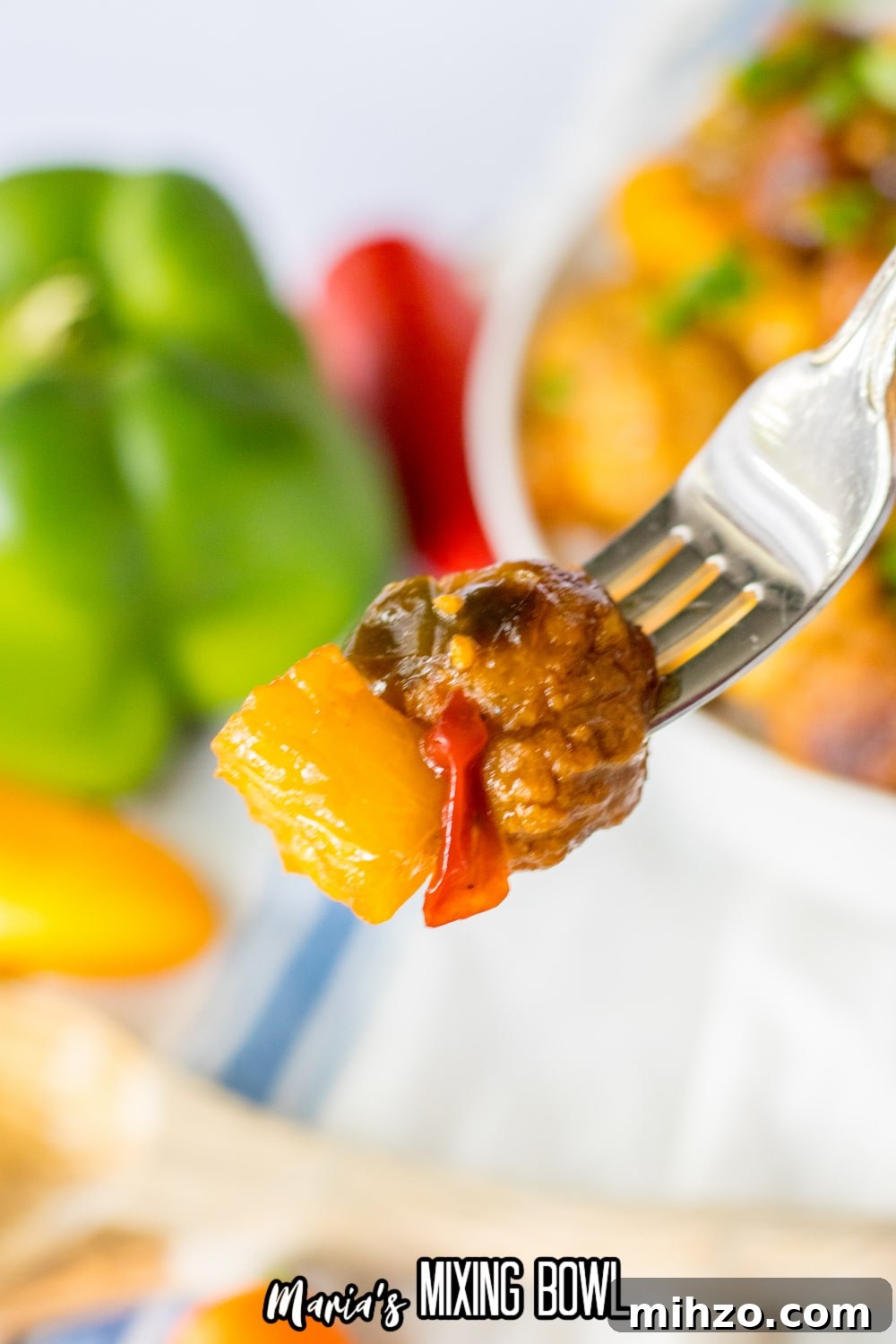 Slow Cooker Hawaiian-Style Pineapple Meatballs 8 meatball, pepper and piece of pineapple held on a fork in the air