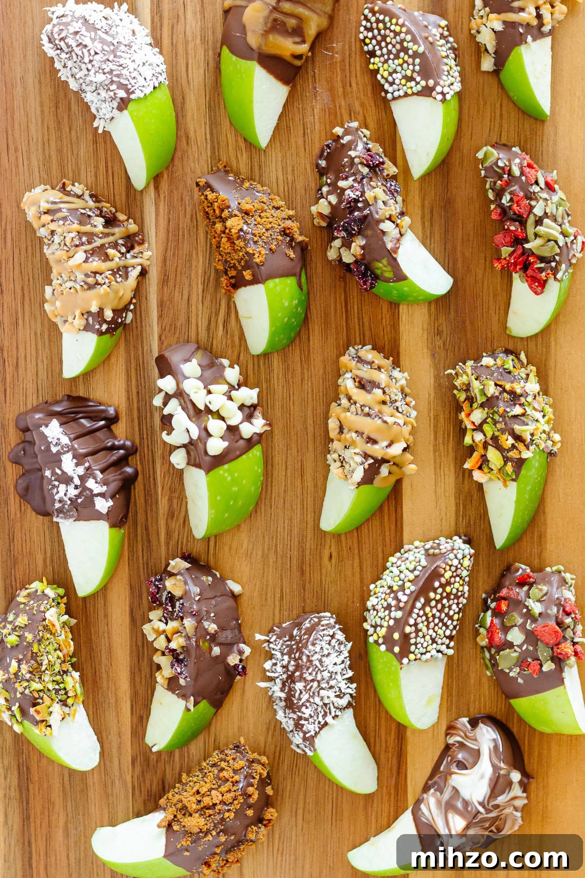 Chocolate-Dipped Apple Slices for Snacks & Parties 12 A variety of different chocolate dipped apple slices on a wood serving board.