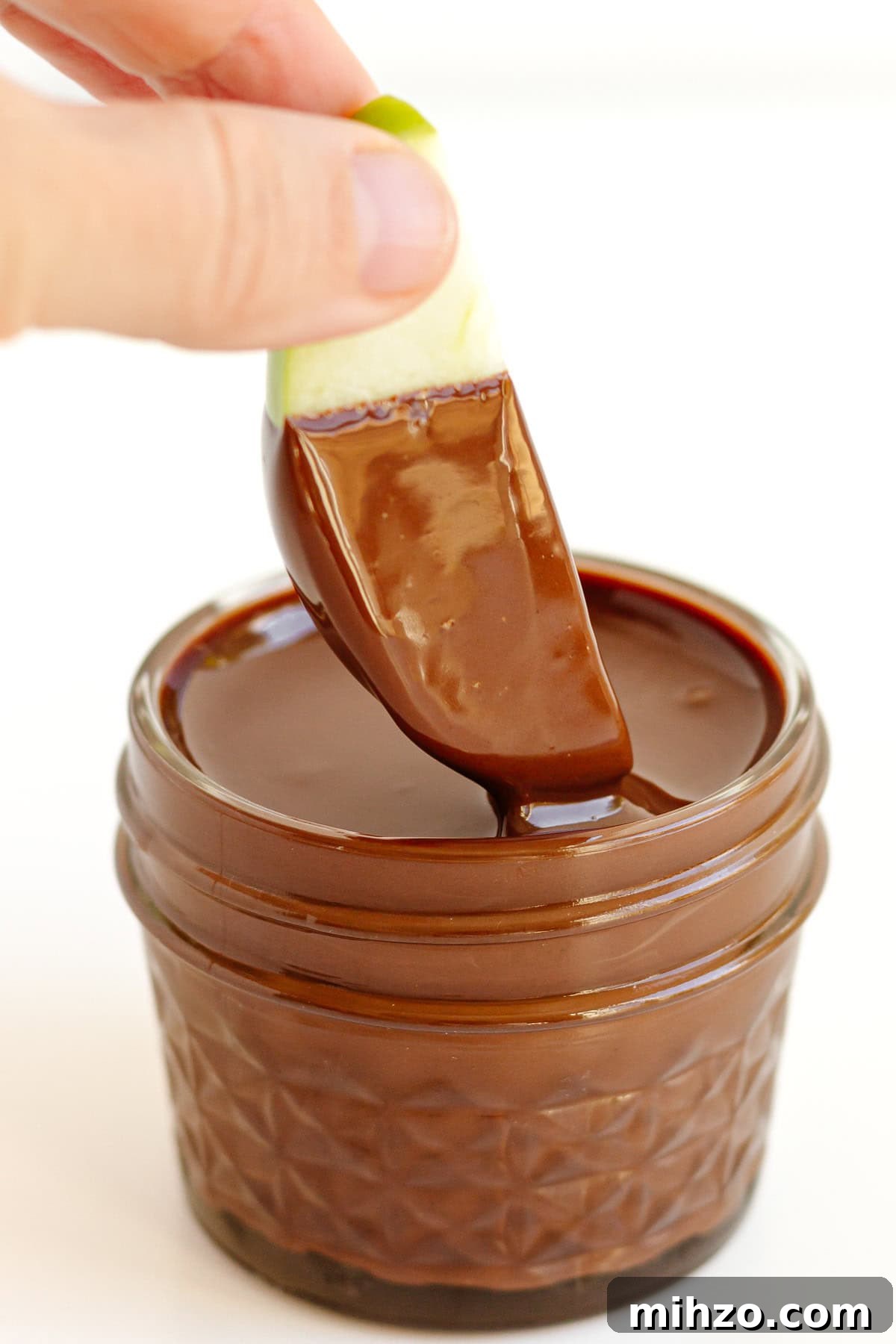 Chocolate-Dipped Apple Slices for Snacks & Parties 3 Apple slice being dipped in melted chocolate.