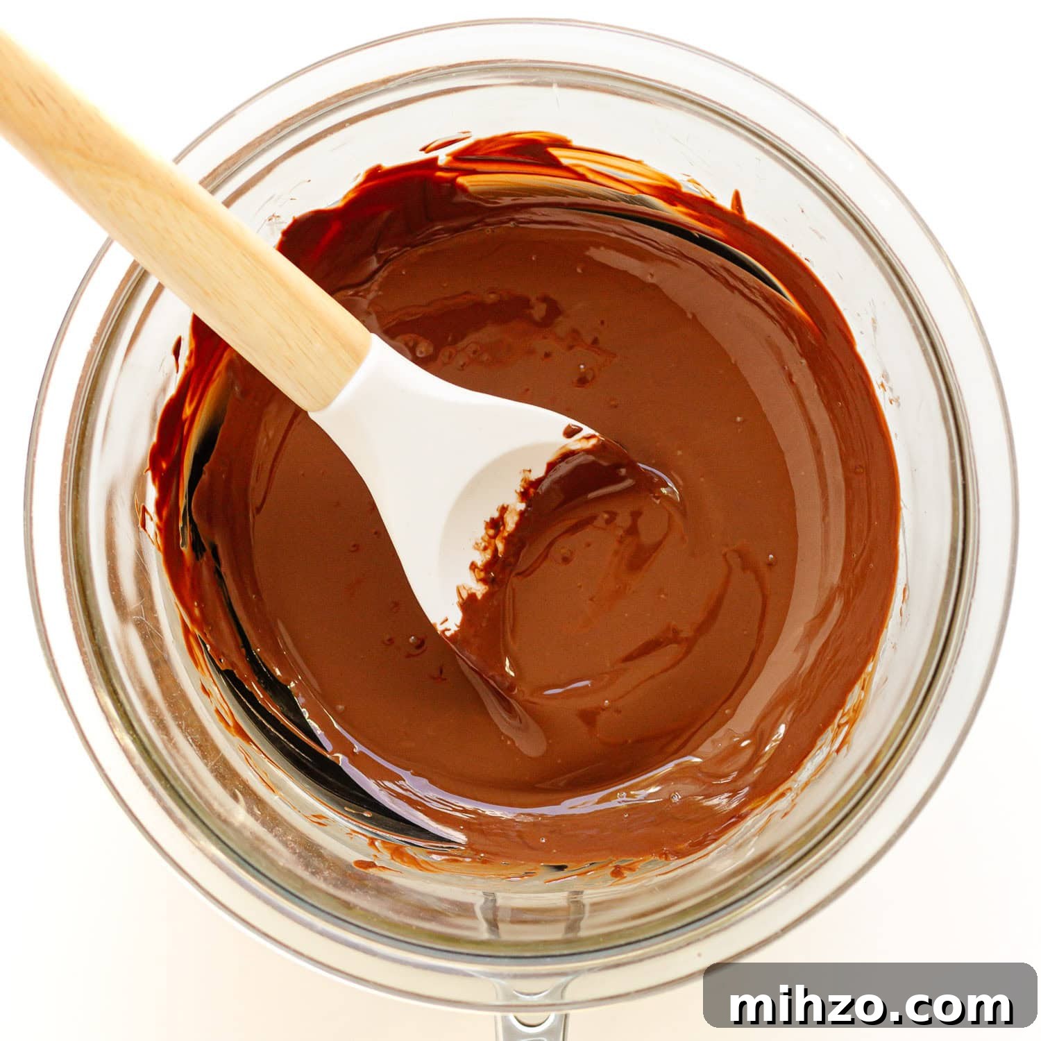 Chocolate-Dipped Apple Slices for Snacks & Parties 6 Melted chocolate in glass bowl over small pot with rubber spatula stirring it.