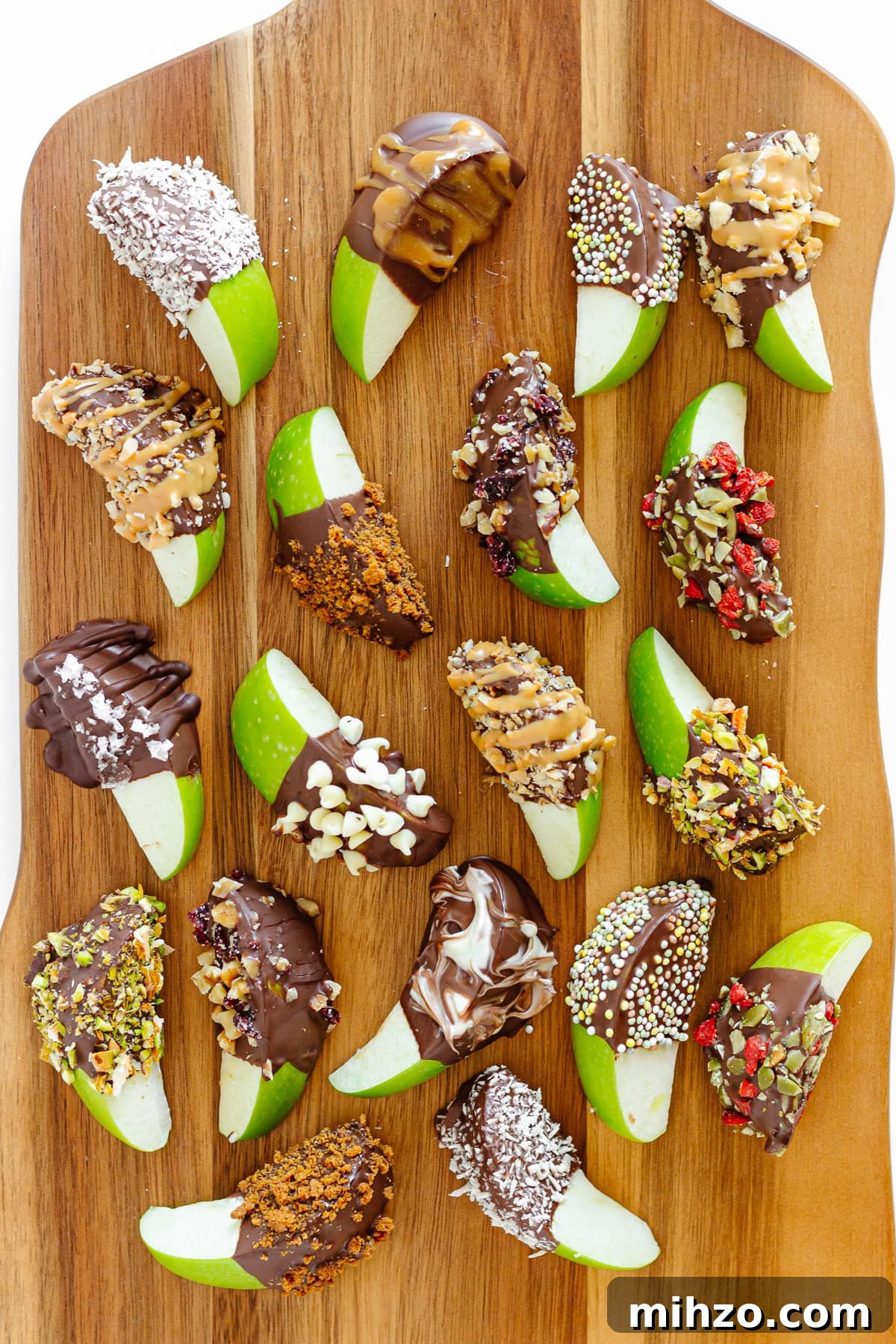 Chocolate-Dipped Apple Slices for Snacks & Parties 9 Variety of chocolate covered apple slices with different toppings being served on a wooden board.
