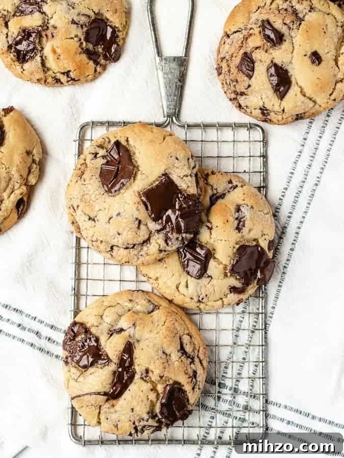 Overhead shot of big soft chocolate chip cookies on a cooling rack with more cookies surrounding