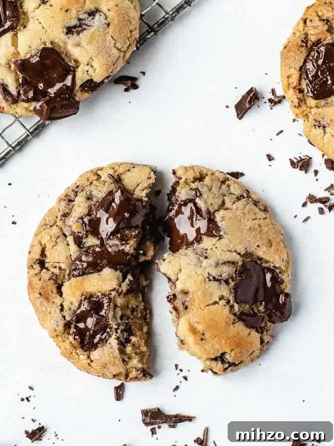 Overhead shot of big soft chocolate chip cookie broken in half with chocolate pieces around