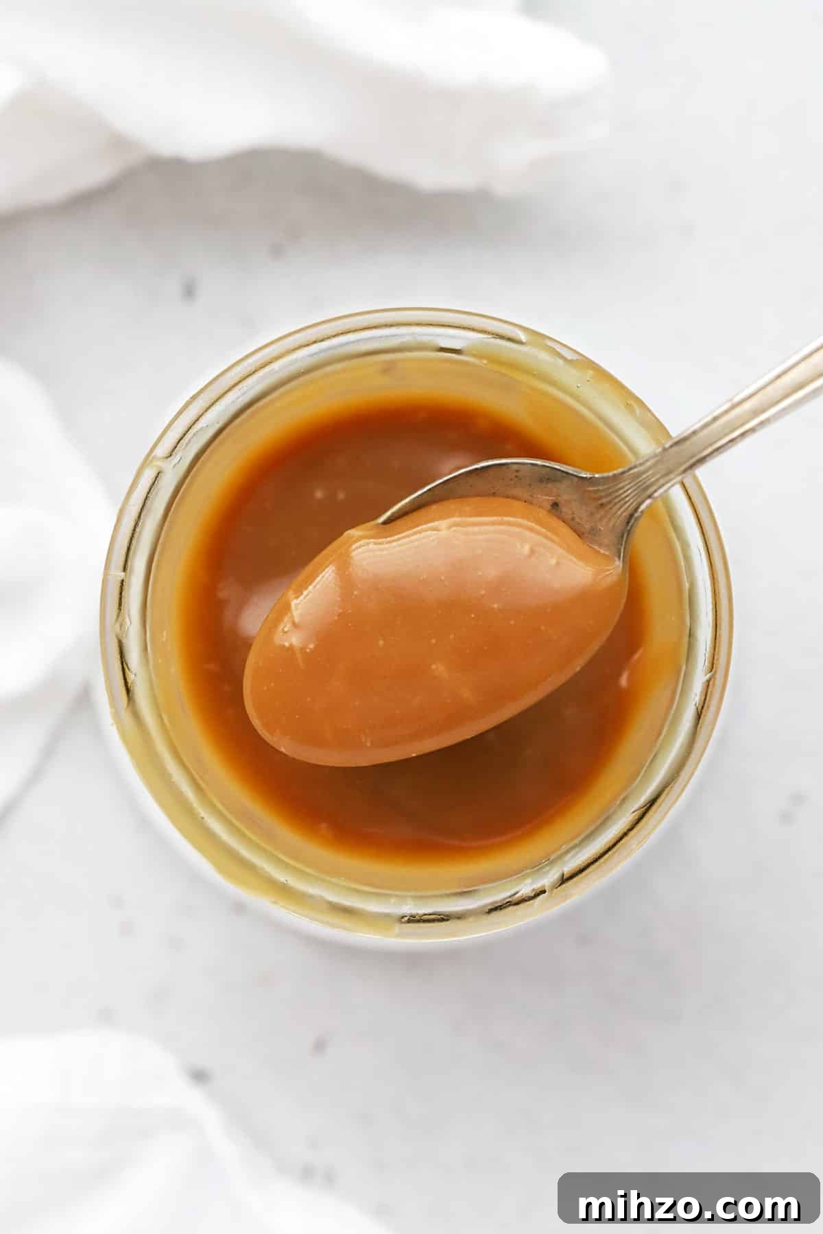 Homemade Caramel Sauce Recipe: Smooth, Pourable & Quick 2 Scooping a spoonful of easy caramel sauce
