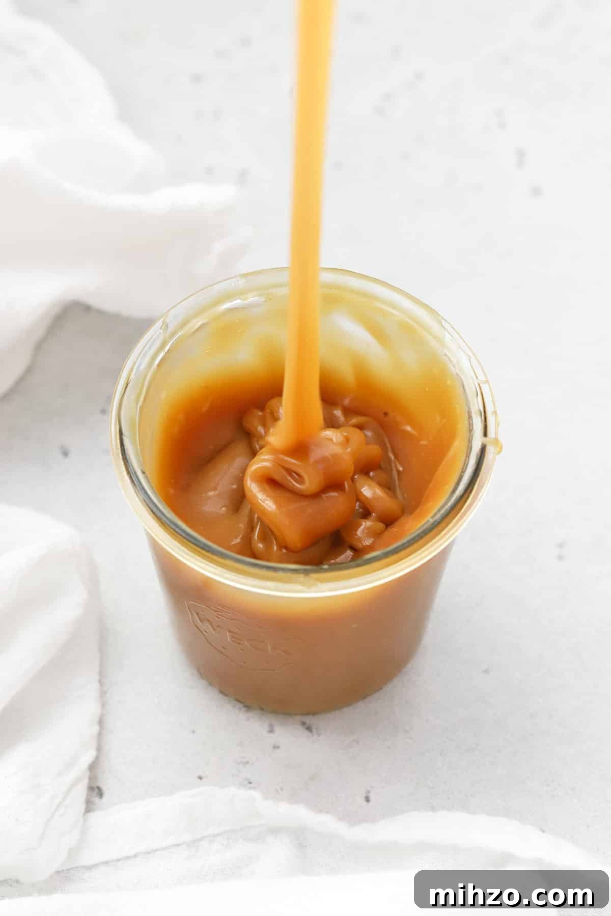 Homemade Caramel Sauce Recipe: Smooth, Pourable & Quick 8 Pouring thick homemade caramel sauce into a jar