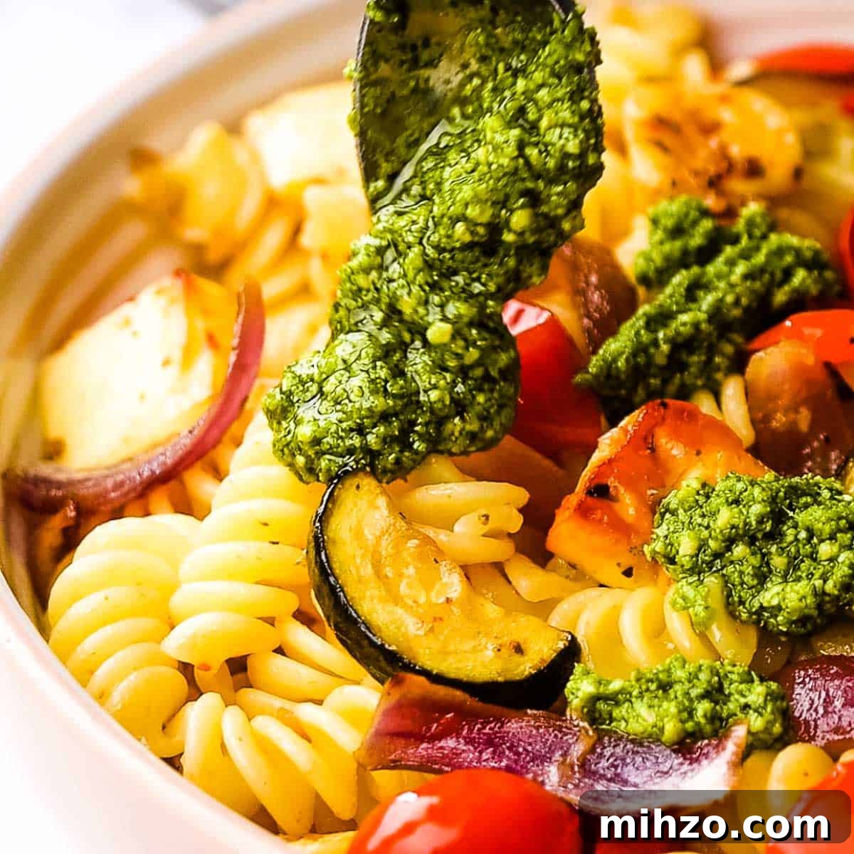 Creamy Halloumi Pasta with Cherry Tomatoes and Basil 12 pesto being added to pasta.