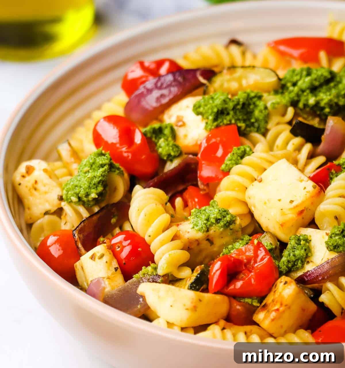 Creamy Halloumi Pasta with Cherry Tomatoes and Basil 13 A bowl of halloumi pasta garnished with pesto