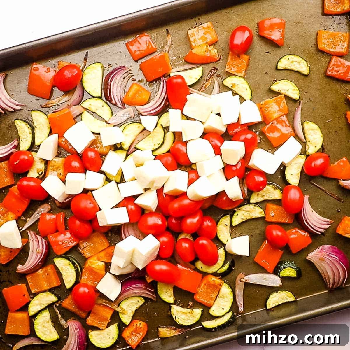 Creamy Halloumi Pasta with Cherry Tomatoes and Basil 9 Halloumi cheese and grape tomatoes on a baking sheet with roasted vegetables.