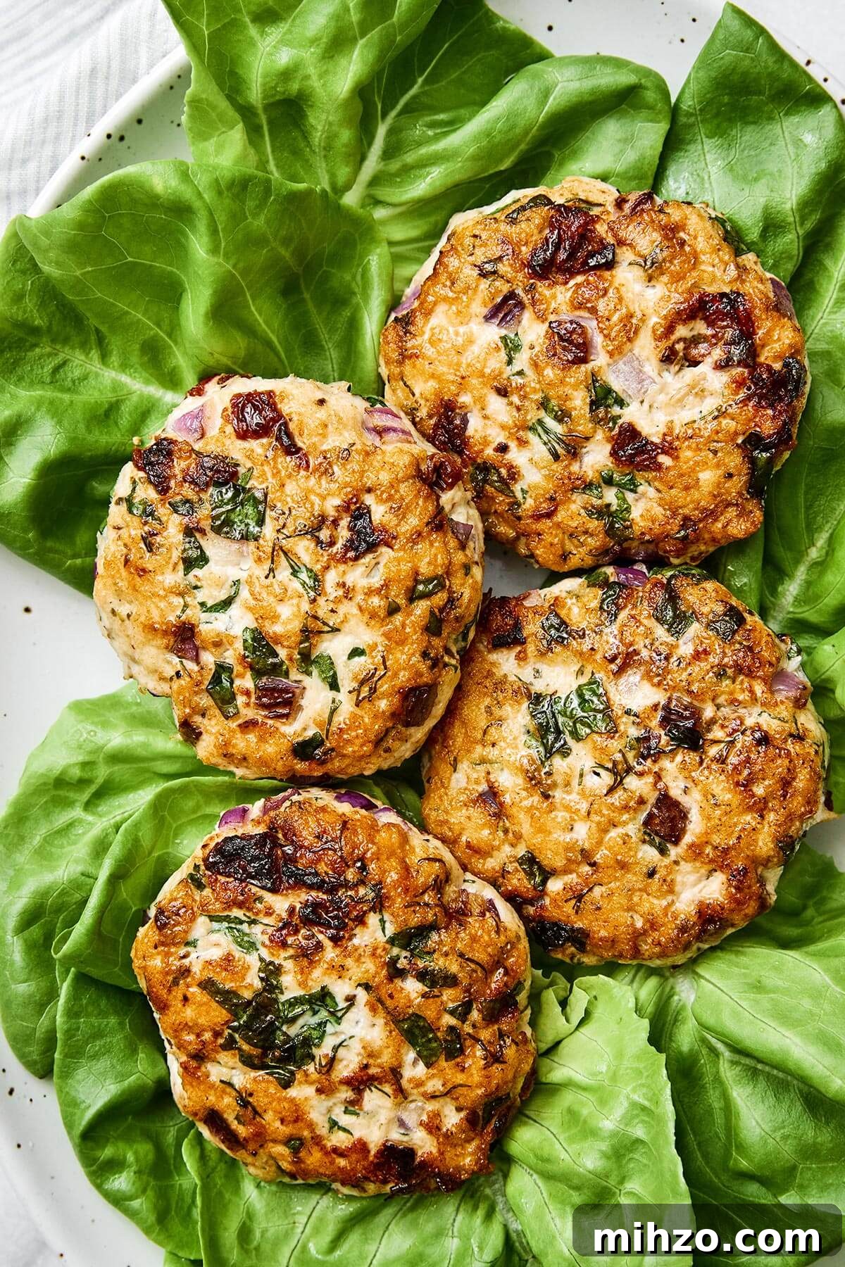 Greek chicken burgers on a plate with lettuce.