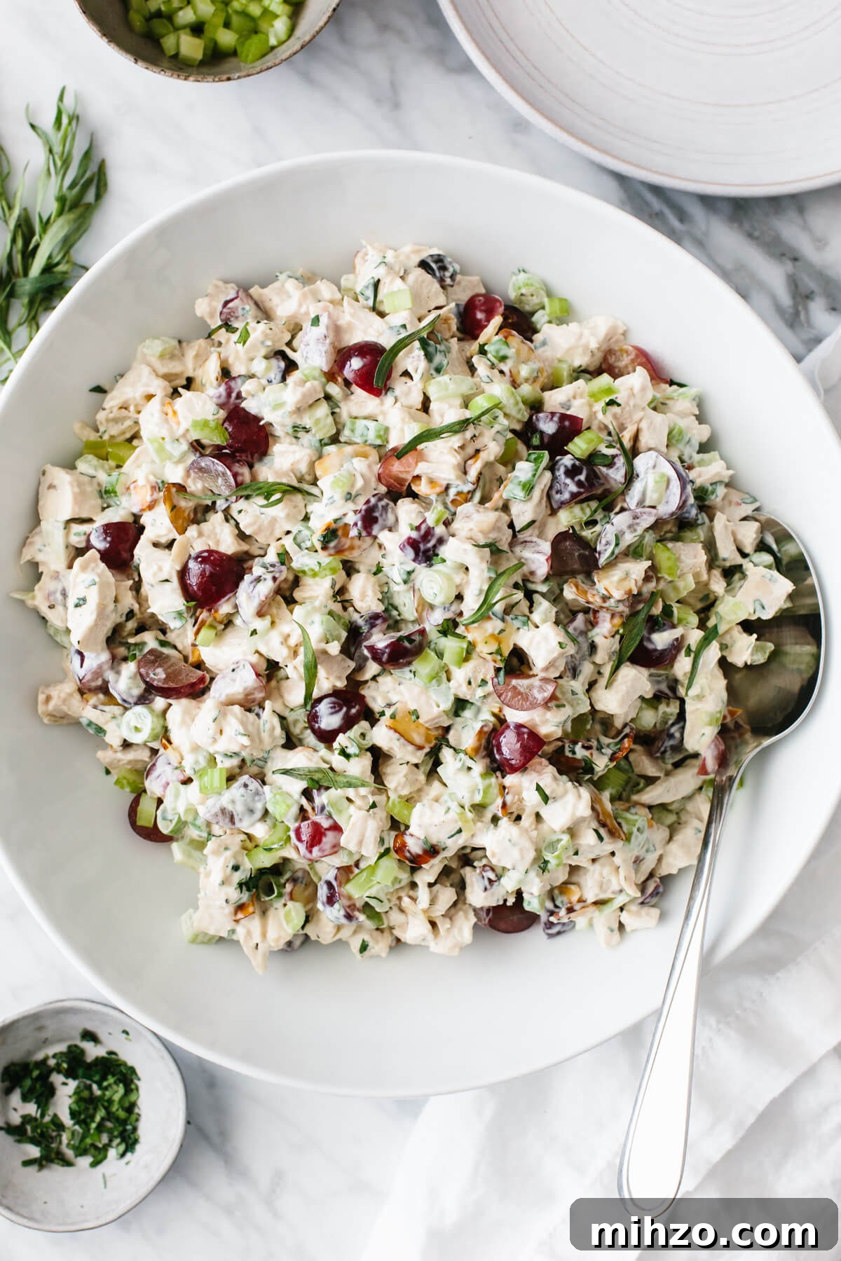 Chicken salad in a white bowl with spoon.