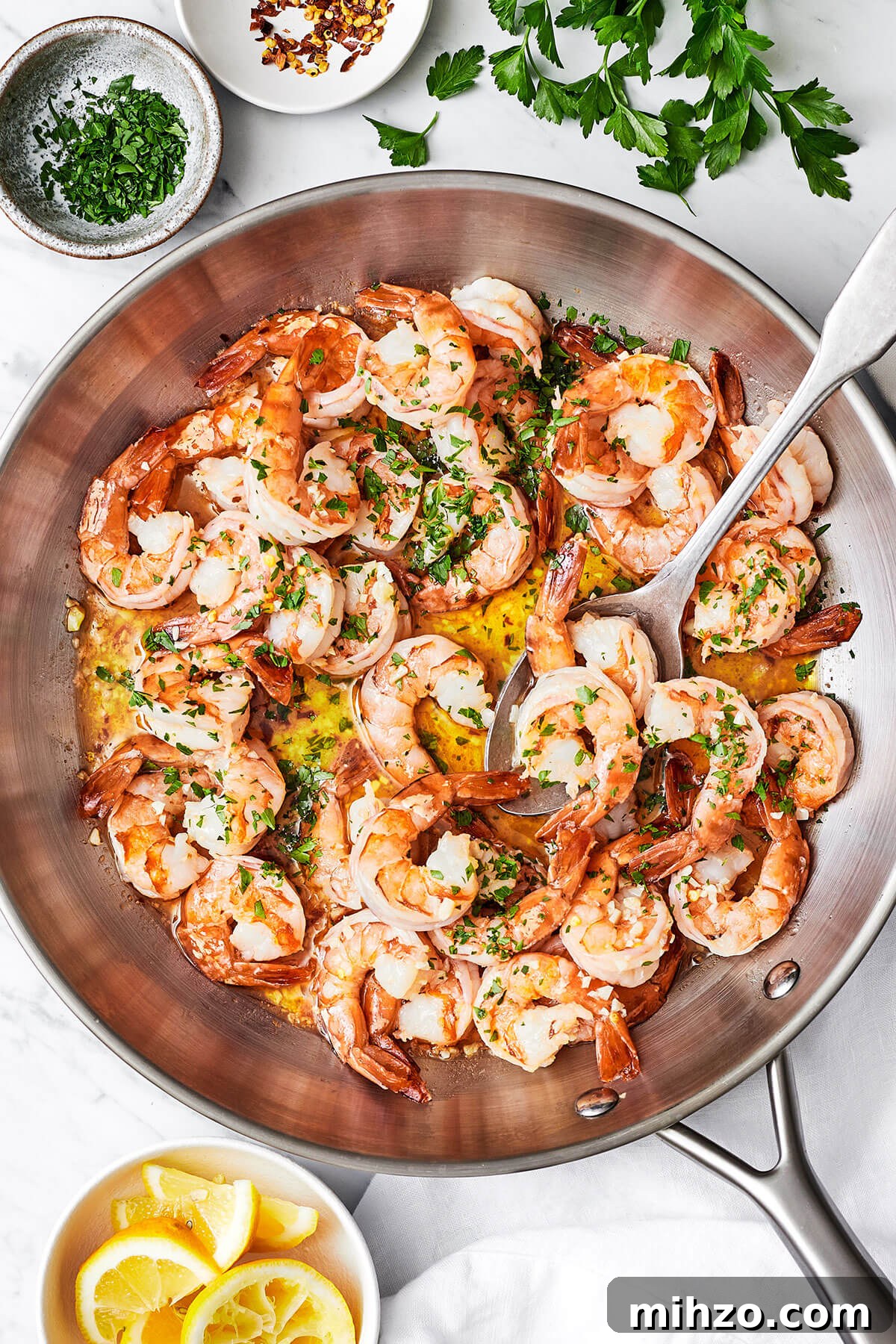 Shrimp scampi in a large pan with a spoon