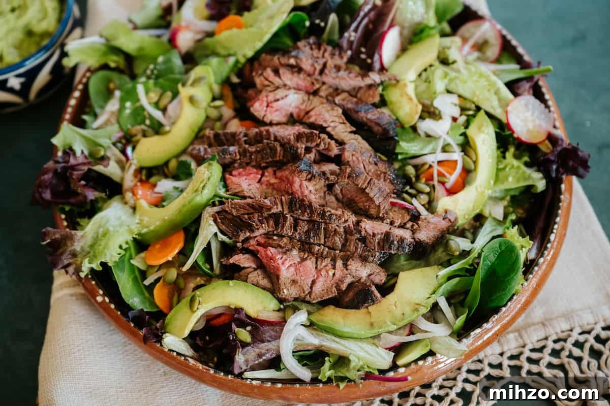 Grilled Carne Asada Steak Salad with Cilantro Lime Dressing 7 overhead shot of a bowl of carne asada salad topped with thinly sliced flank steak.