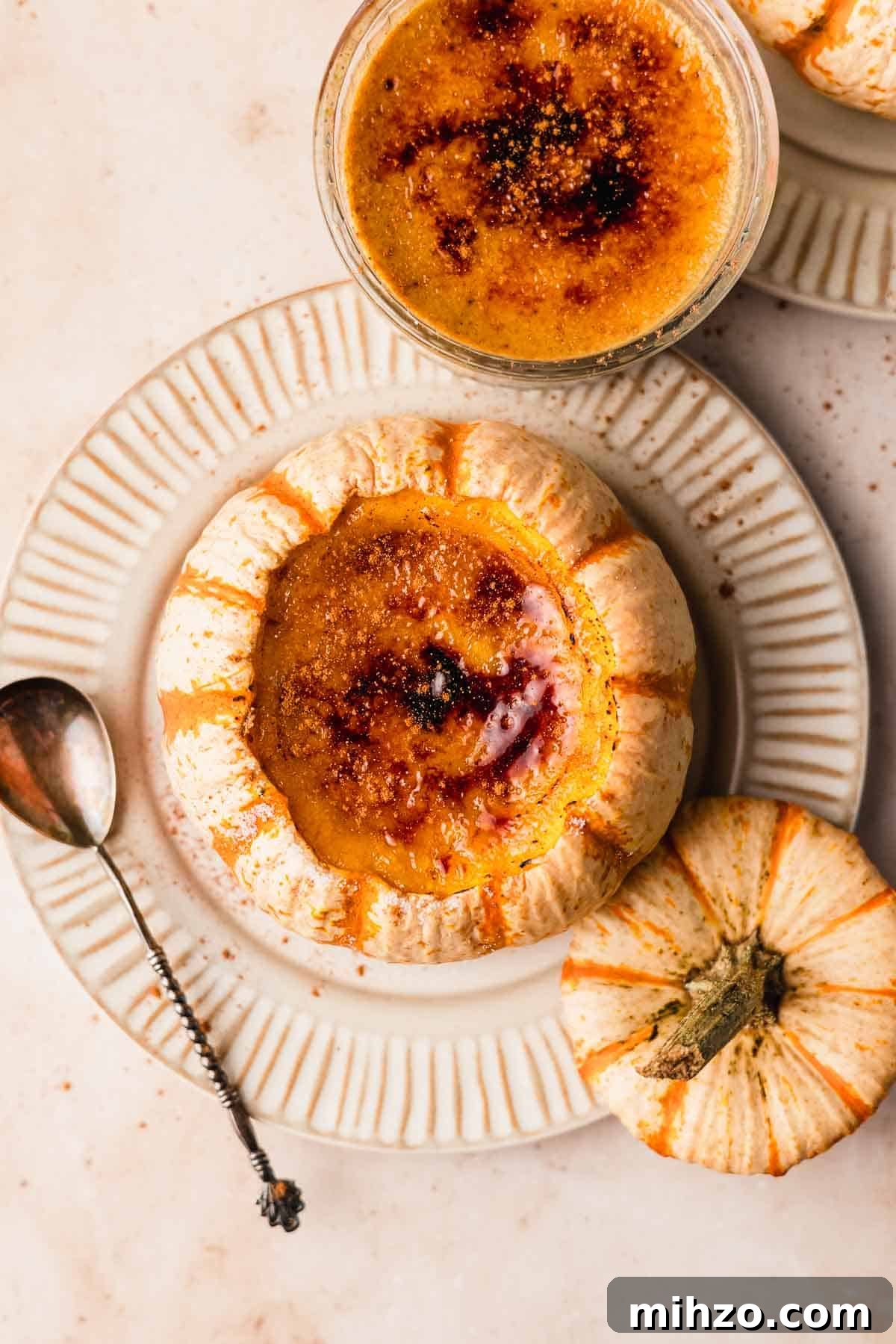 Pumpkin Crème Brûlée Recipe — Silky Fall Dessert Tutorial 12 creme brulee with burnt sugar top inside pumpkin on top of a ribbed plate