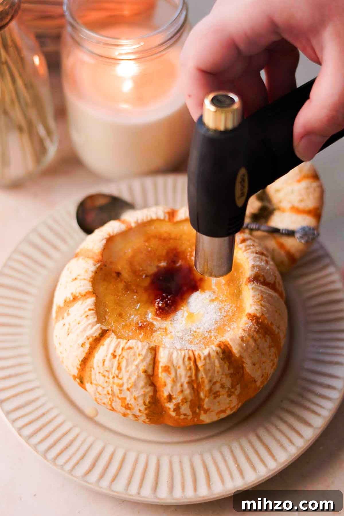 Pumpkin Crème Brûlée Recipe — Silky Fall Dessert Tutorial 10 torching top of creme brulee inside of pumpkin with a kitchen torch