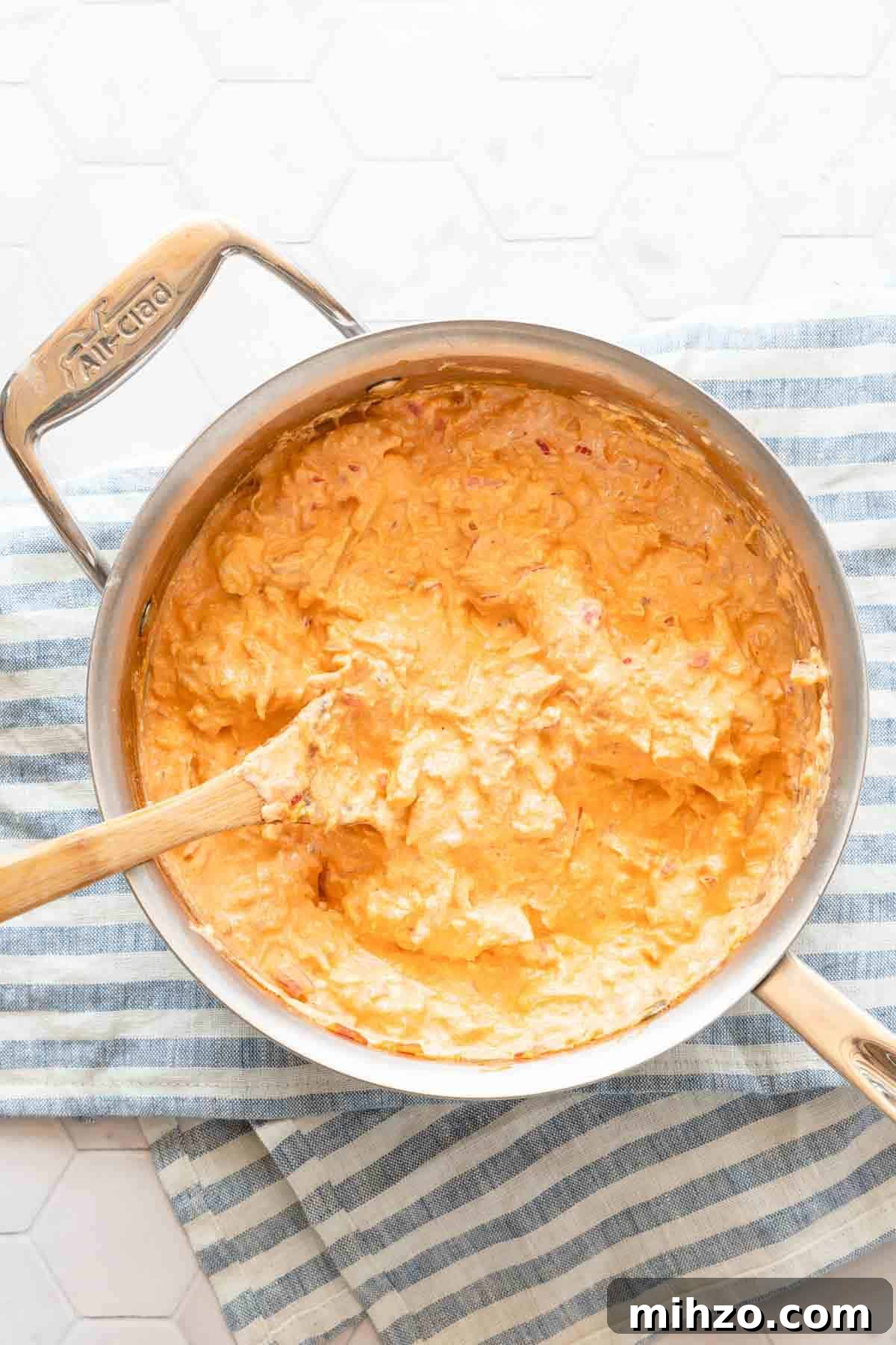saucepan of buffalo chicken dip with wooden spoon inside the pan.