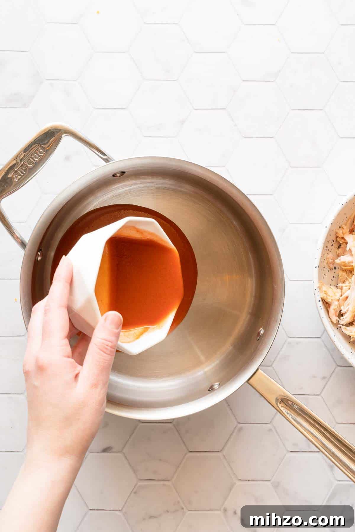 hot sauce being poured into a saucepan.