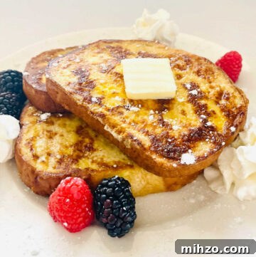 protein french toast with slice of butter, raspberries, blackberries and whipped cream
